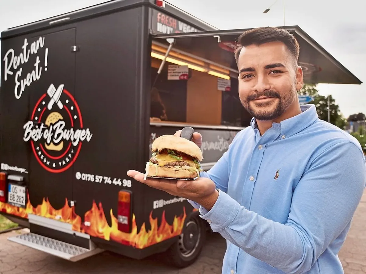 Rasim Kubilay Yildiz, Inhaber von Grilln Chill, mit frisch zubereitetem Burger vor dem Foodtruck
